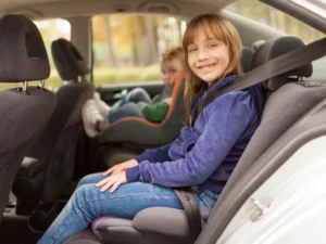 Children buckled into car seats in the back seat of a family car